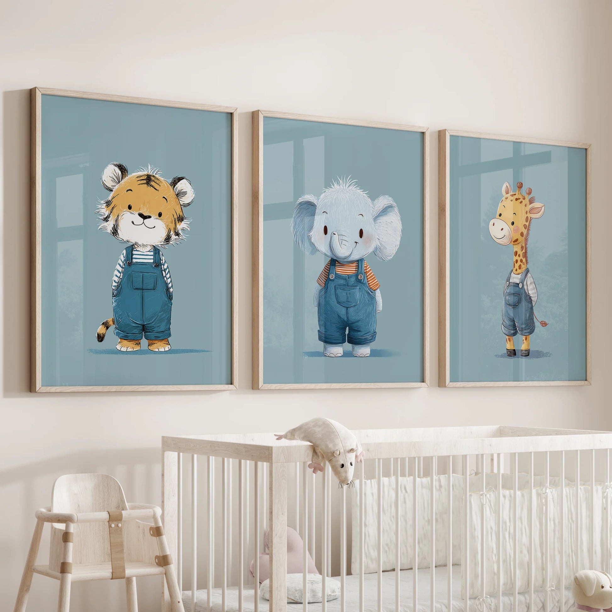 Three blue safari animal prints in slim wood frames hang above a nursery cot, adding a soft jungle note to the space.