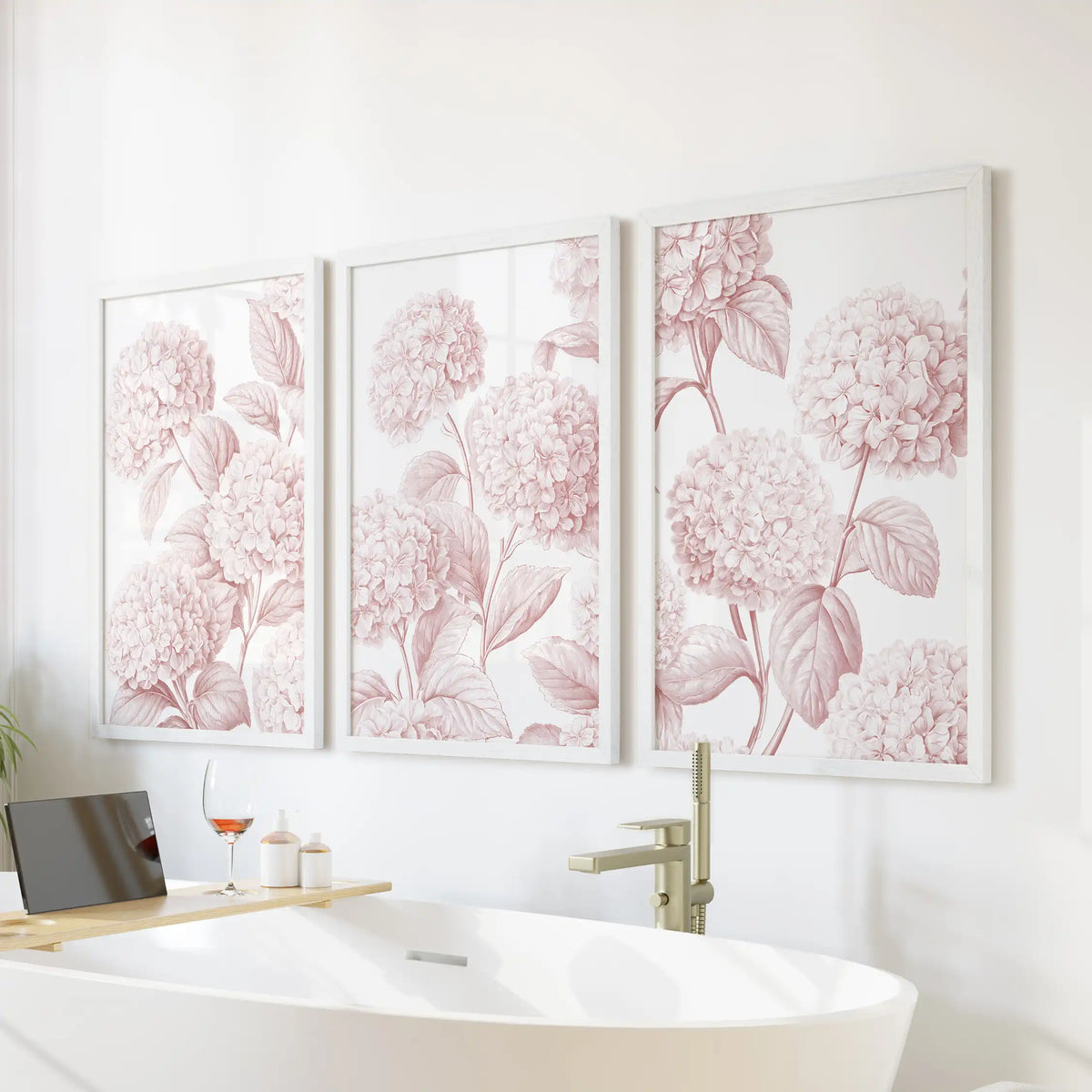 Above a freestanding bathtub, three white frames hold pink hydrangea prints.
