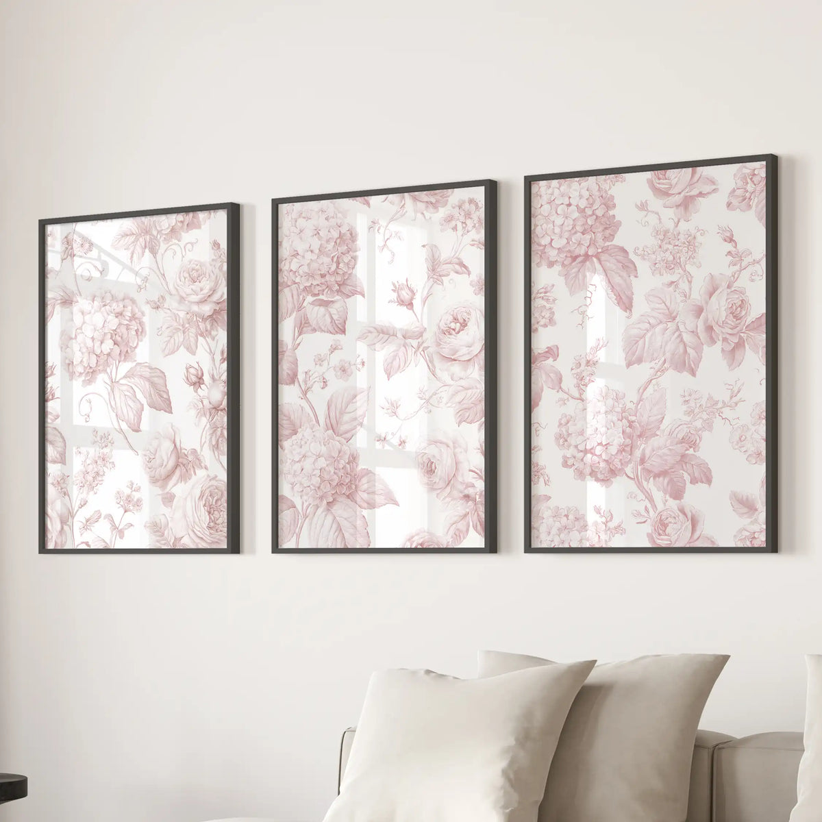 The three black-framed prints above a sofa are filled with pink roses and hydrangeas, linked by fine leafy stems on cream backgrounds.