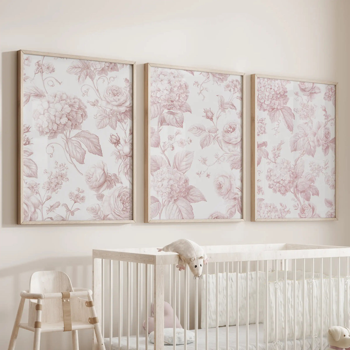 Above a nursery crib, three pink rose and hydrangea prints hang in oak frames.