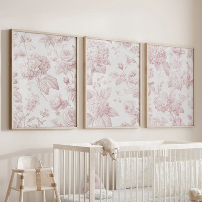 Above a nursery crib, three pink rose and hydrangea prints hang in oak frames.