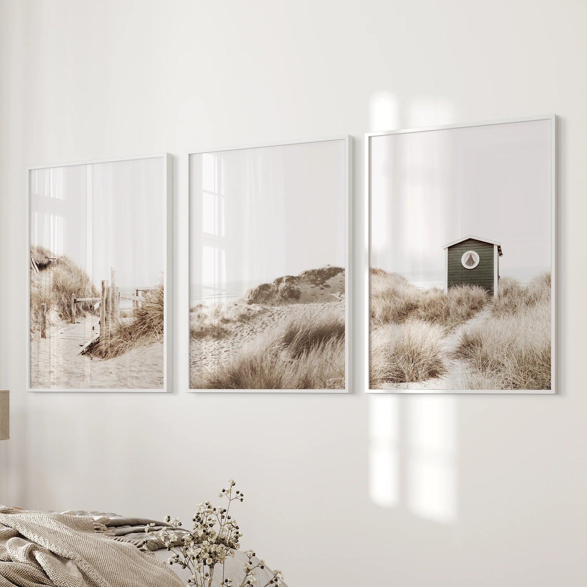 Dried coastal grass three-piece wall art set in white frames warms the bedroom wall, layering soft texture and sandy neutrals with a boho ease.