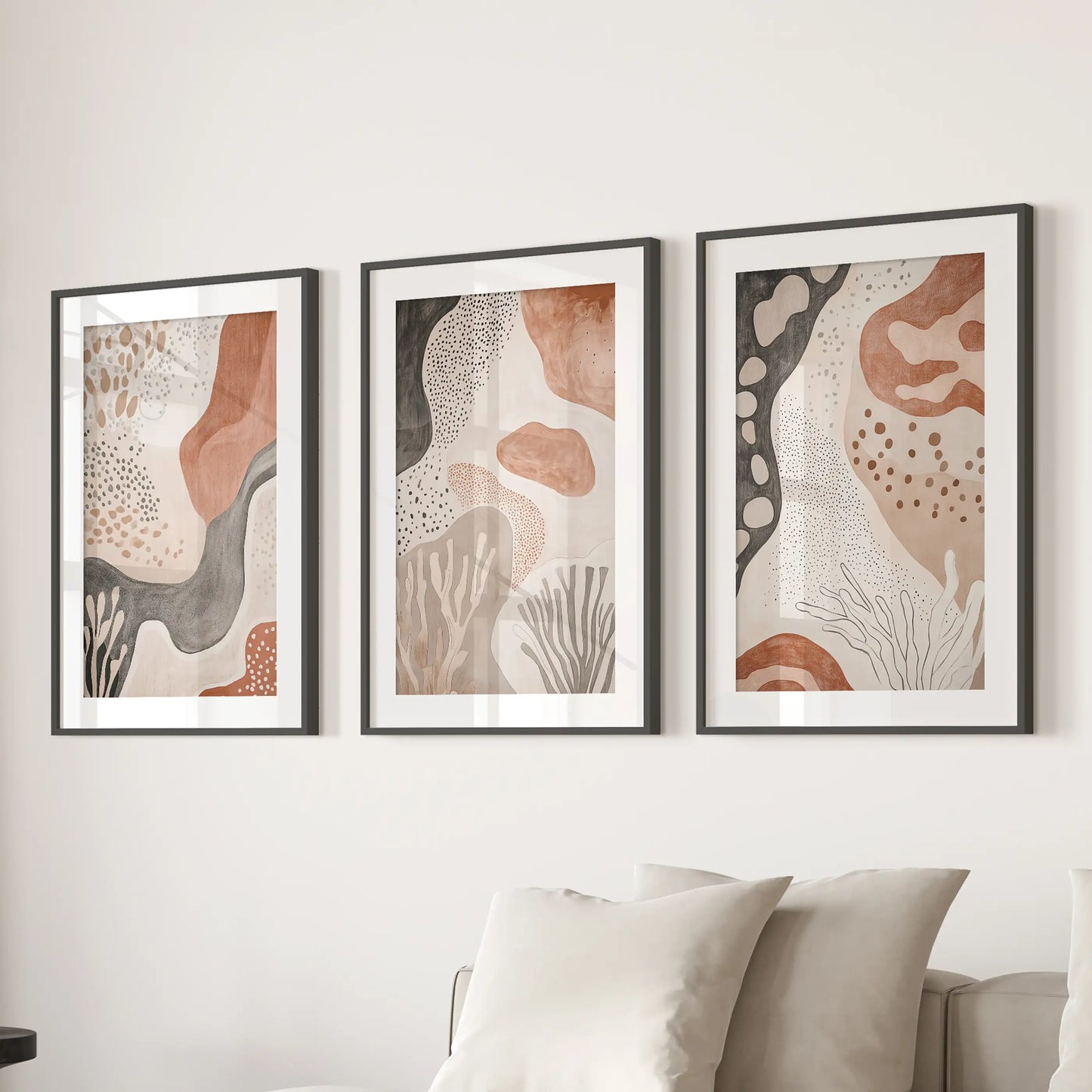 Boho abstract shapes, a three-piece art print set in black frames with mats, brings warm structure above the sectional in the lounge.