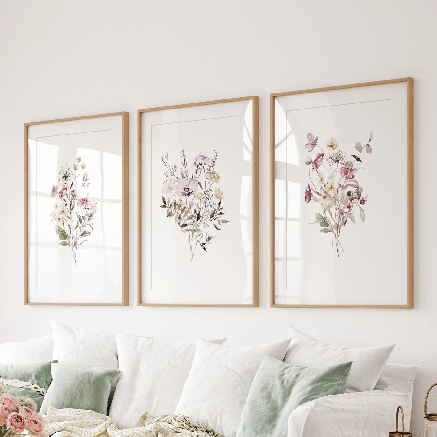 A relaxed set of three boho botanical artworks in wood-matted frames creates easy warmth above the couch.