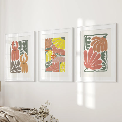 Boho flower market posters, a 3-piece set, hang next to the bedroom’s bed wall in white frames with wide mats, letting the terracotta florals breathe and feel modern.