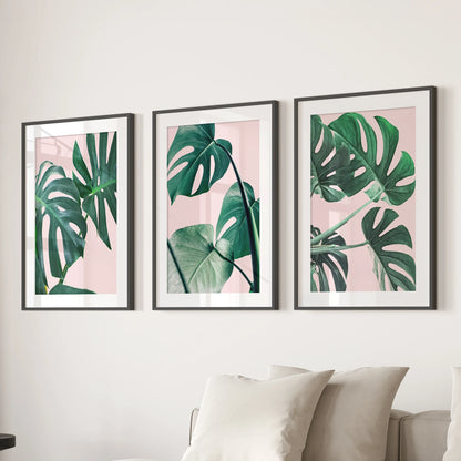 A boho botanical wall trio of monstera prints, matted and black-framed, centers the living-room wall above the sectional in tidy balance.
