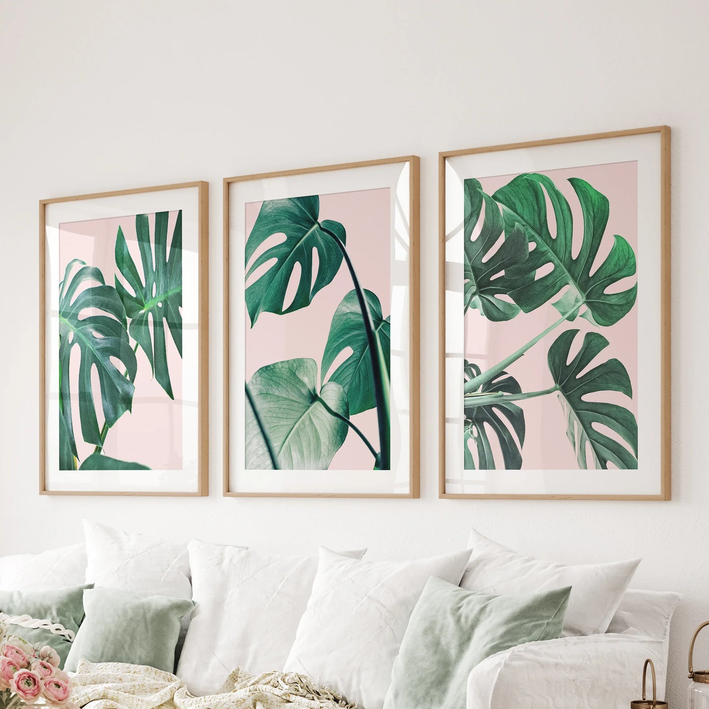 Wood-matted monstera leaf prints in a three-piece set span the living-room wall above the couch, offering crisp boho-tropical style.