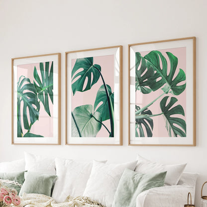 Wood-matted monstera leaf prints in a three-piece set span the living-room wall above the couch, offering crisp boho-tropical style.