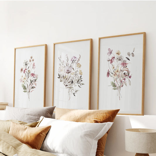 Three oak-framed floral prints float above the bed, their soft colors warming the bedroom with subtle natural tone.