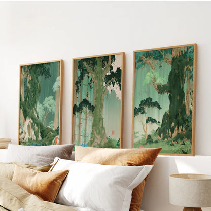 A set of three green botanical scenery art prints in light oak frames hangs above the headboard in a bedroom.