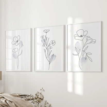 Three white-framed botanical line drawings mount beside the bed, giving the bedroom wall a spare, modern softness.
