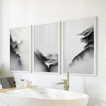 Set of three white-framed art prints showing minimalist mountain scenes adds soft tranquility above the tub in the bathroom.