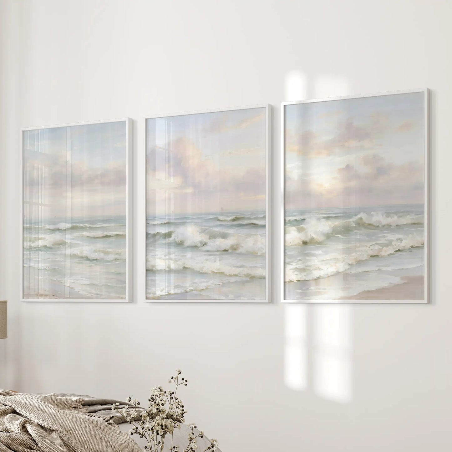 A three-piece white-framed wall art set of neutral waterscapes quiets the bedroom atmosphere beside the bed.