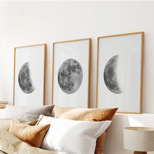 A set of three black-and-white moon artworks in natural oak frames rests above the bed, warming the room with refined celestial tone.