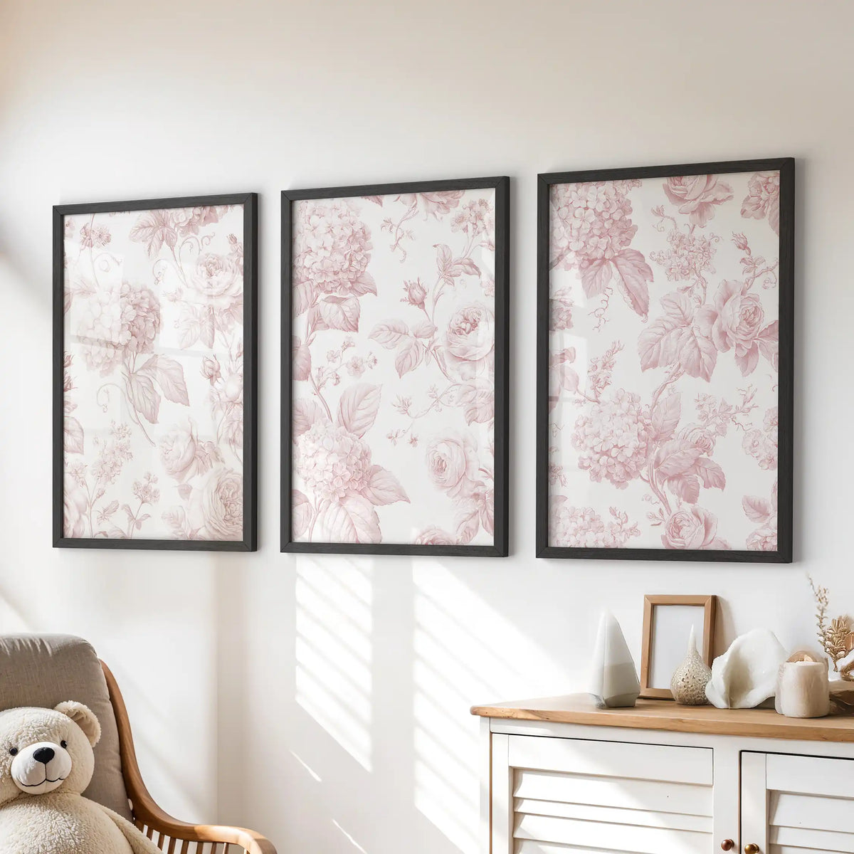 Above a dresser, three black-framed prints show pink roses and hydrangea patterns.