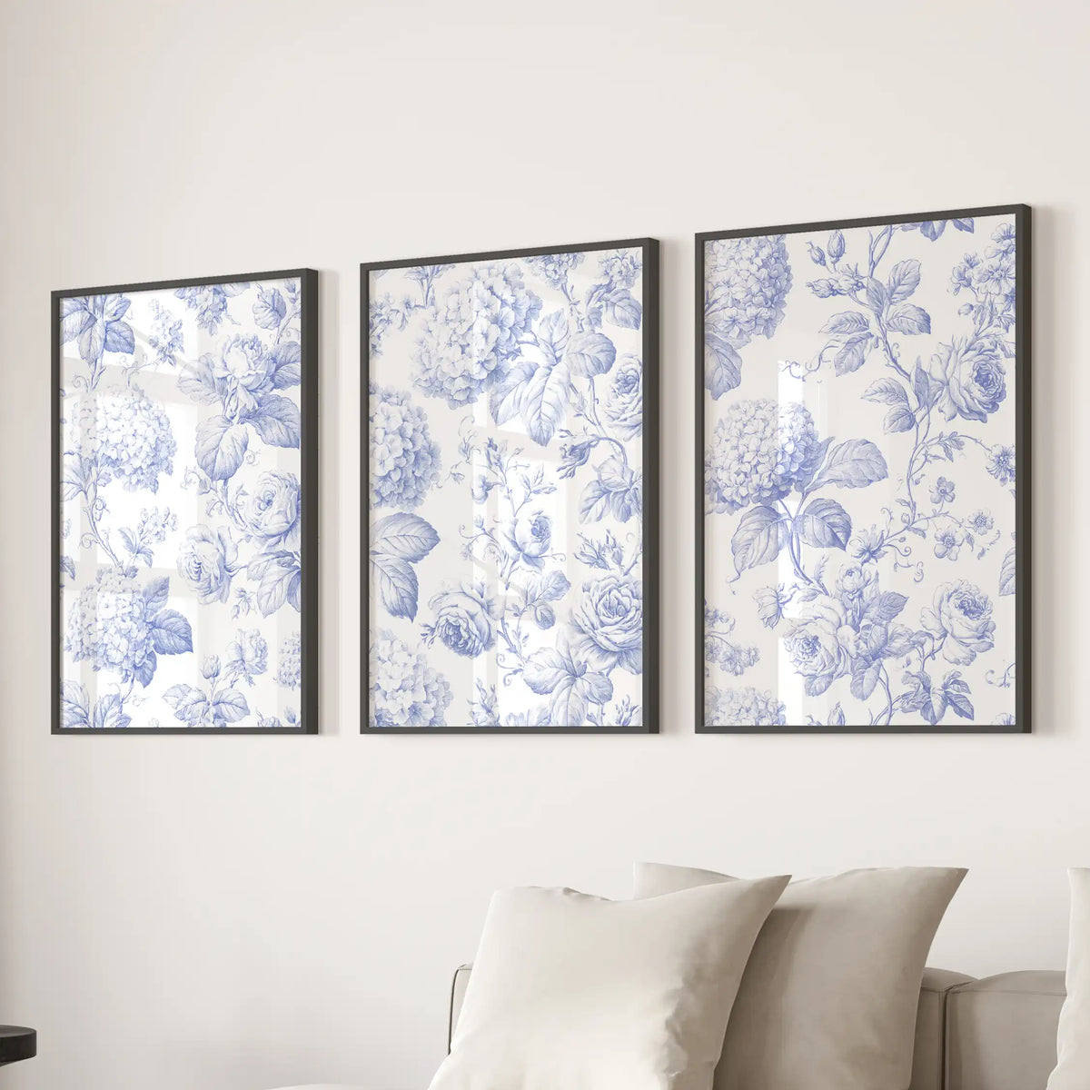 Above a sofa, three black-framed prints show blue roses and hydrangea clusters.