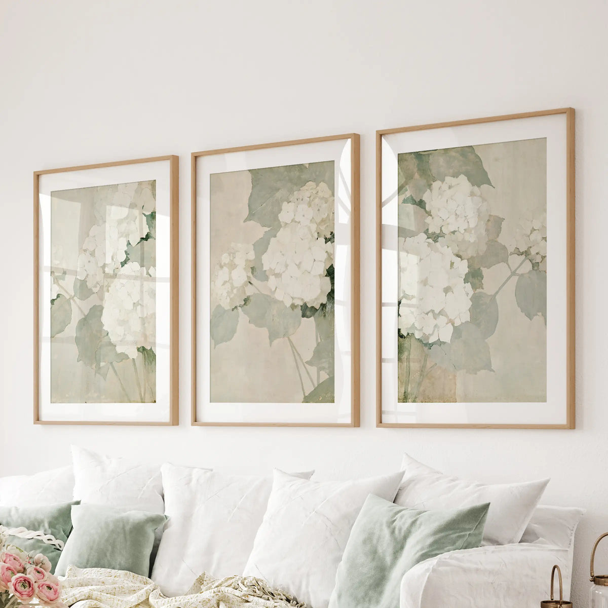 Three-piece gallery wall of vintage garden botanicals in thin matted wood frames, hanging over a sectional sofa in the living room.