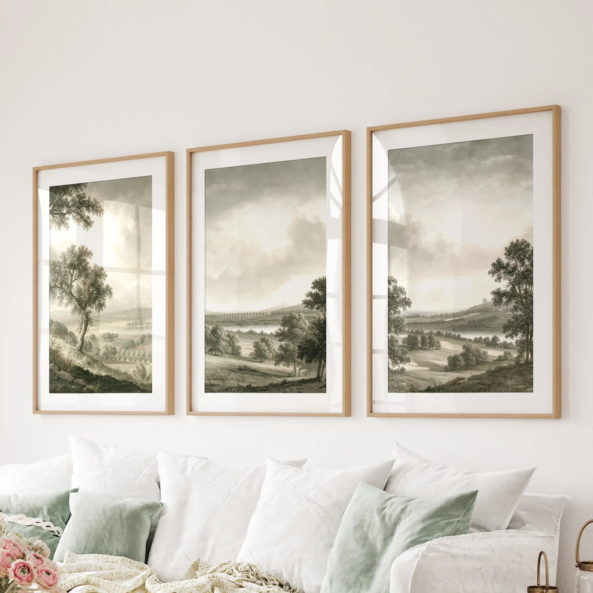 Rural landscape wall art in a three-piece set, shown in matted wood frames over a sofa in a sitting room.