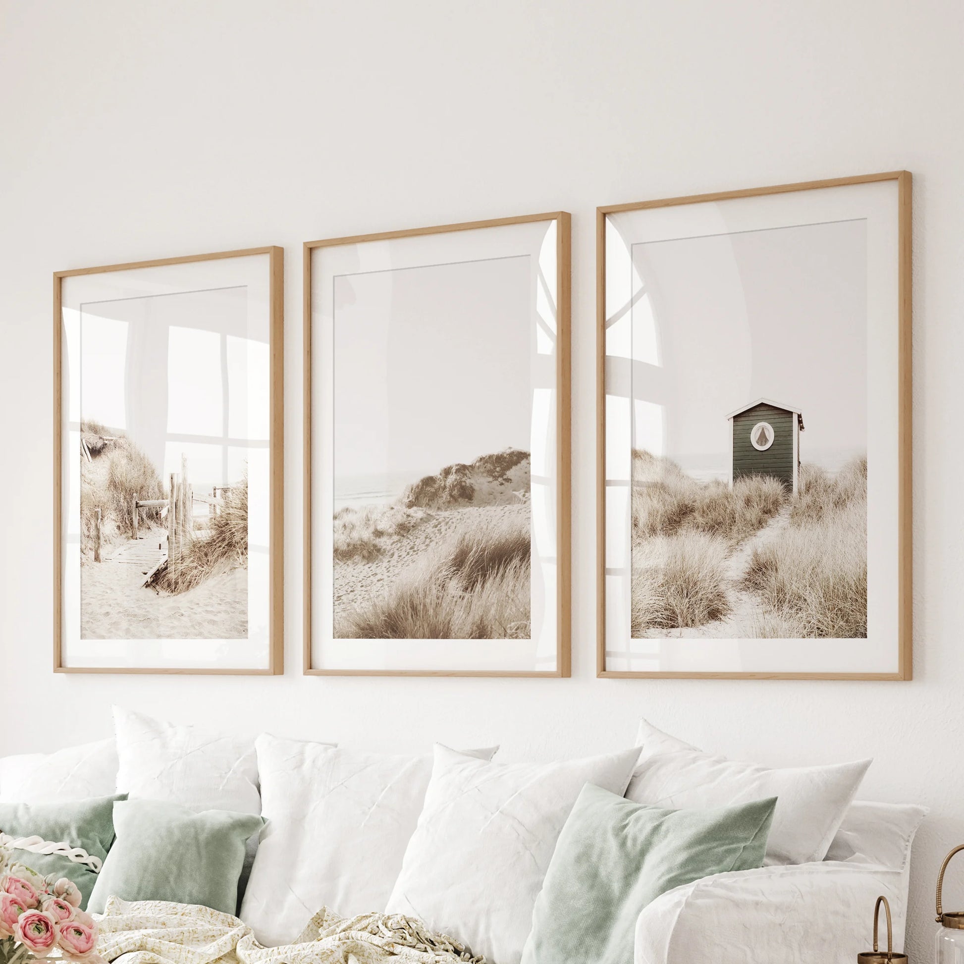 A light coastal seascape poster trio in thin wood frames with mats floats over the family-room couch, keeping the palette open and airy.