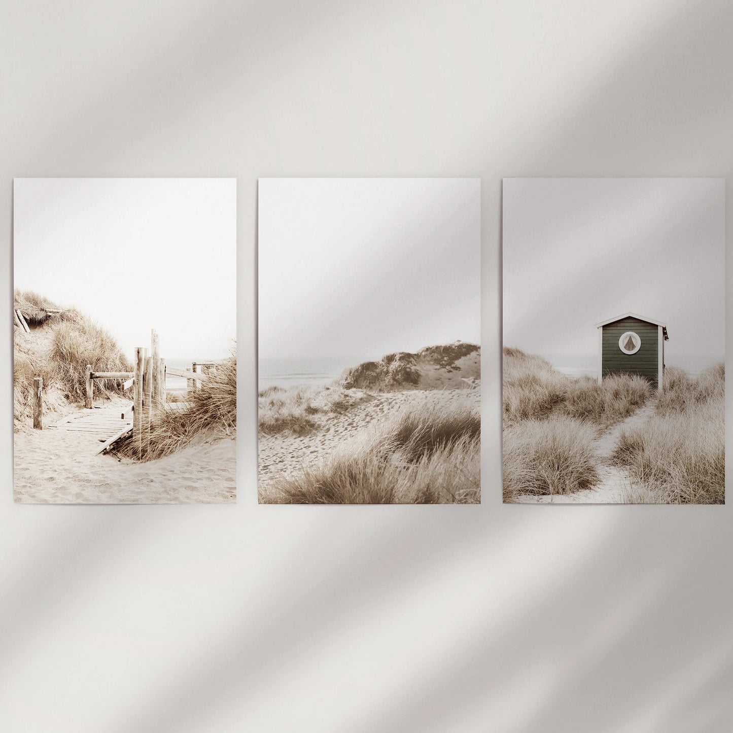 Unframed wall prints of sunlit dunes and shoreline form a minimalist 3-print set, leaving the beach palette airy and quietly relaxed.