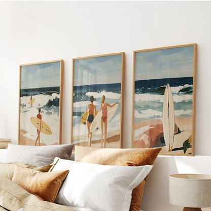 A trio of women-surfing prints in slim wood frames floats above the bed, letting a relaxed coastal breeze drift through the bedroom.