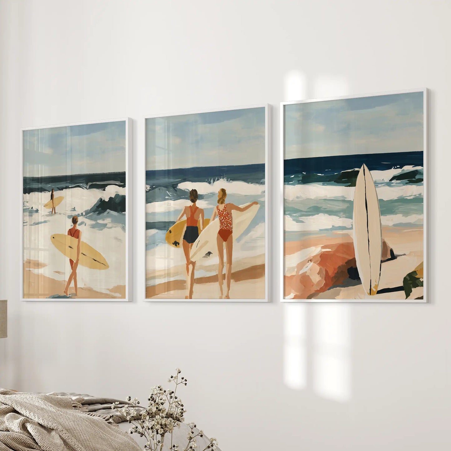 Three coastal beach prints in crisp white frames glow softly on a bedroom wall, blending sand and sea tones into a calming accent.