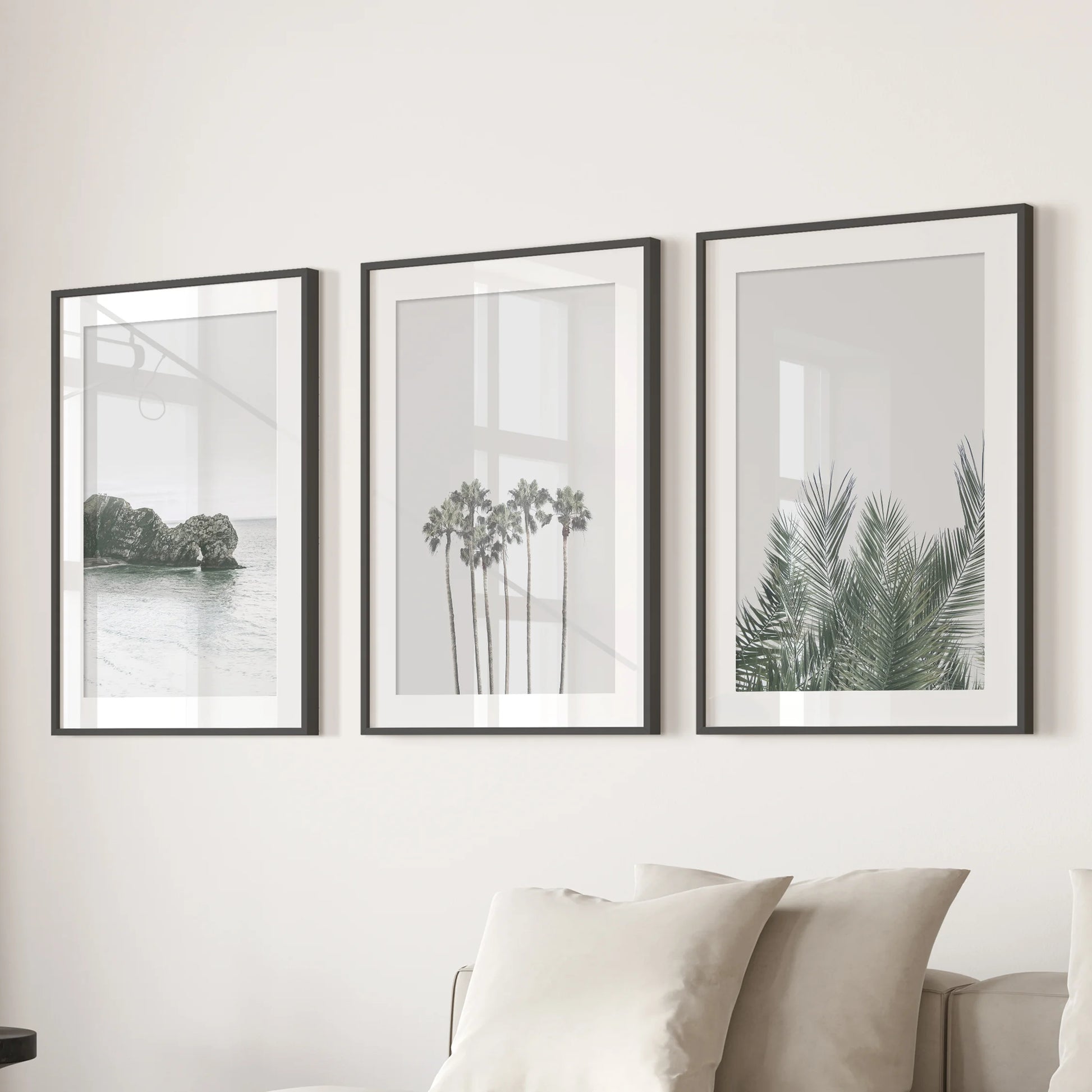 Pastel seaside landscape set of three prints softens the family room, shown in black mat frames and arranged over the sectional.