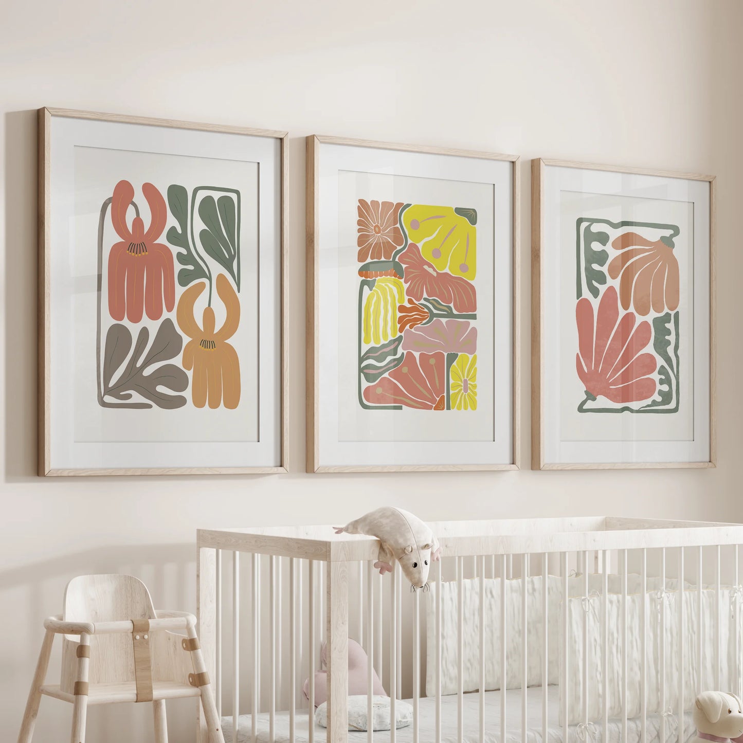 Vintage-style flower prints in a 3-piece wall set hang above the nursery cot, matted in natural oak frames to soften the space with gentle botanical charm.
