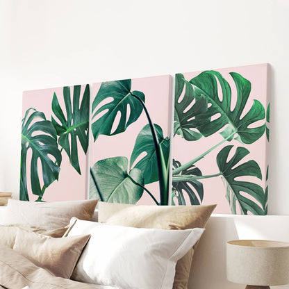 Boho botanical monstera print trio on unframed canvas hangs above the bedroom headboard, offering minimalist wall art with blush-pink leaf texture.