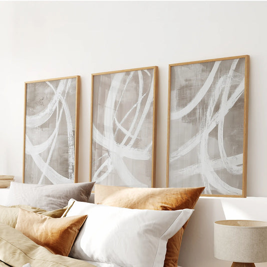 Neutral beige brush strokes artwork, 3-piece set in light wood frames, spans the bedroom wall over the headboard for a calm, tonal look.