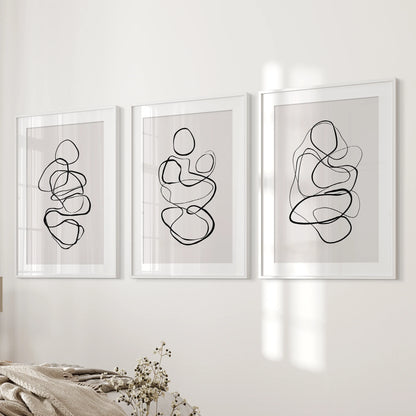 A 3-print gallery wall of abstract line drawings, matted and white-framed, aligns neatly beside the bedroom bed for a polished finish.