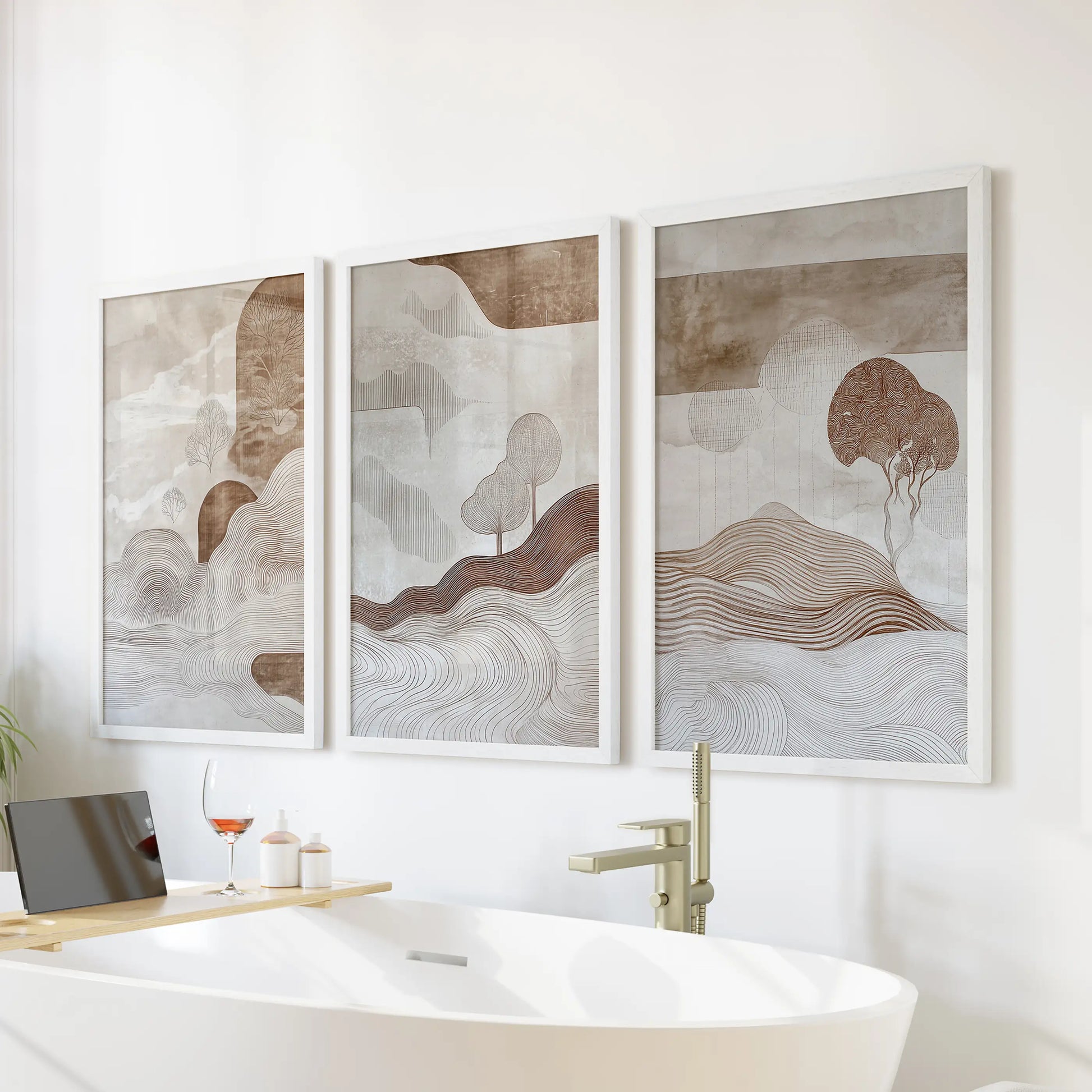 A three-piece set of earth-toned abstract artwork in white frames adds serene wall art above the bathtub for a spa-inspired bathroom.