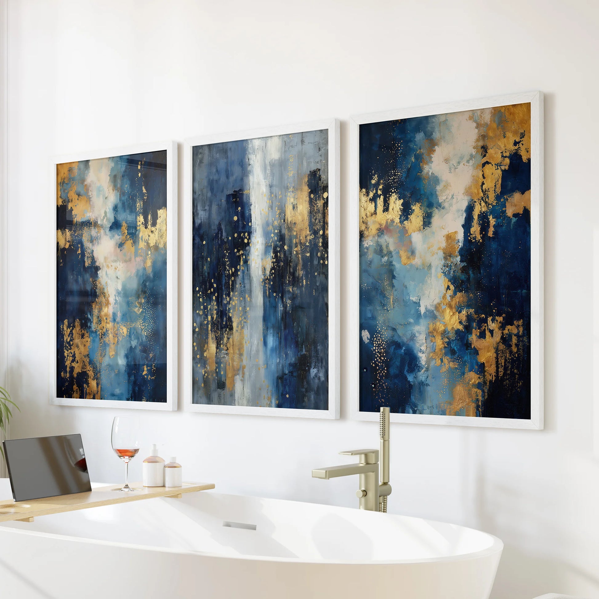 Minimalist blue and gold art set in a white-framed three-print collection rests as wall art over the soaking tub, bringing calm texture to the bathroom.