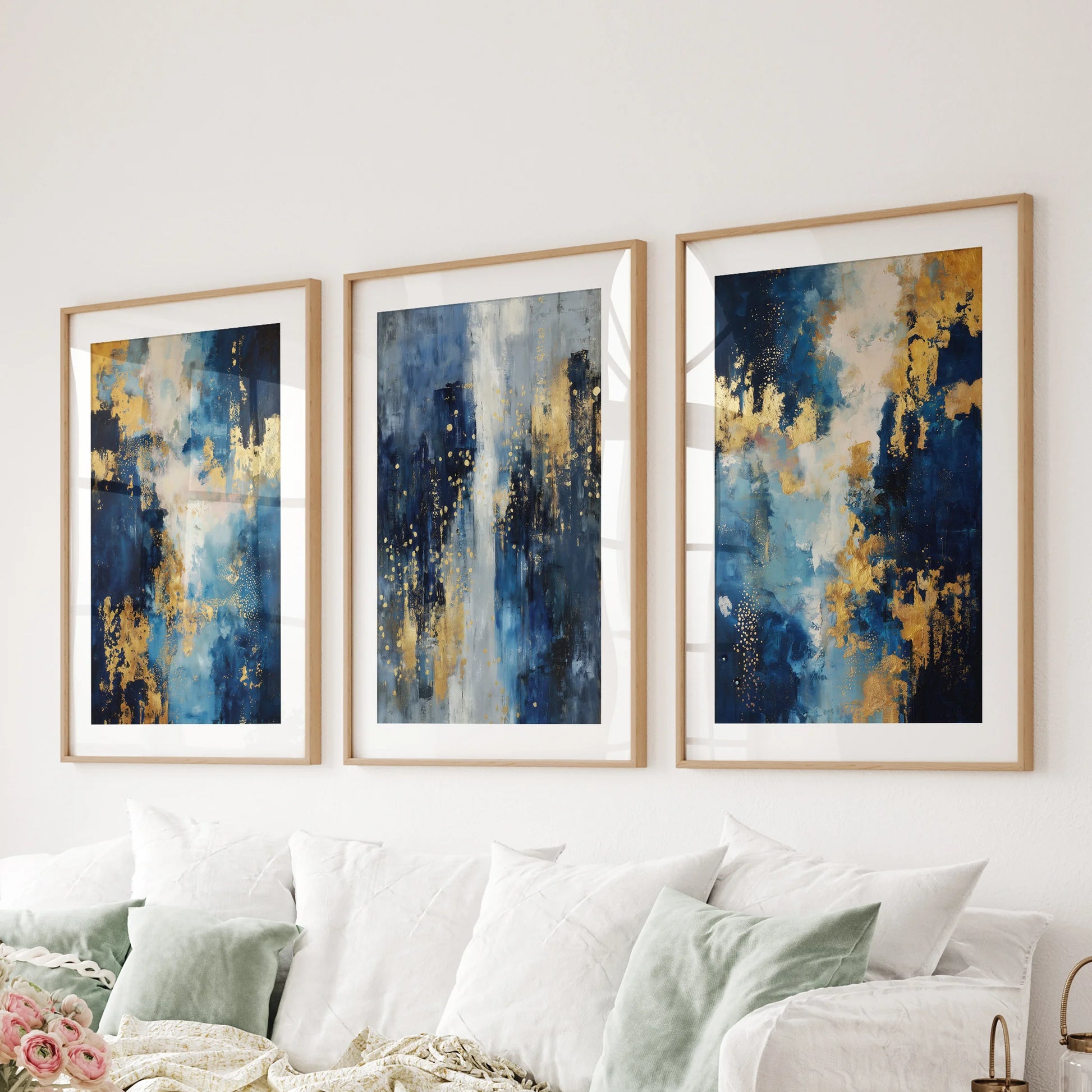 A set of three oak-matted wall art prints in navy and gold stretches over the family-room couch for a warm, refined gallery feel.