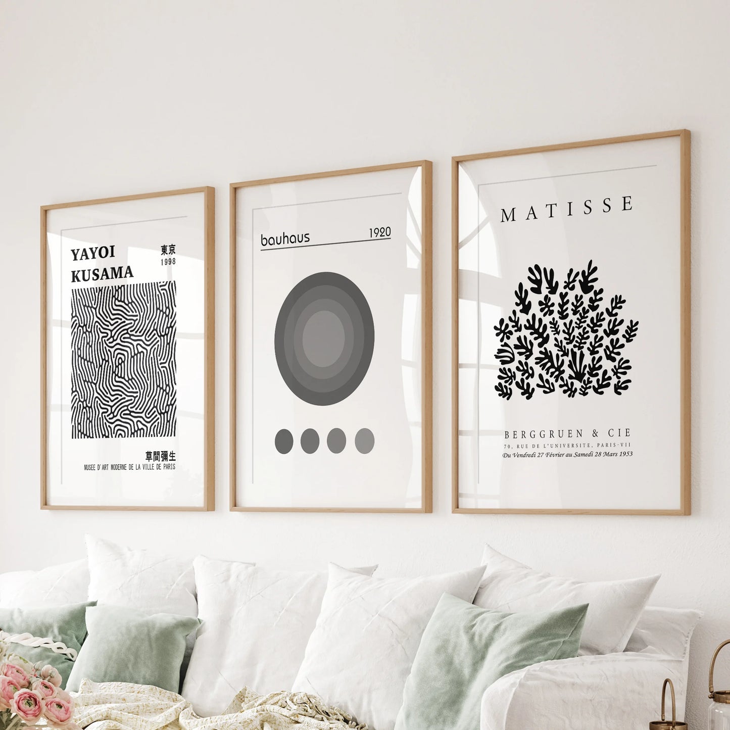 A three-print set of black-and-white abstracts in wood-matted frames stretches above the sectional, grounding the family room cleanly.