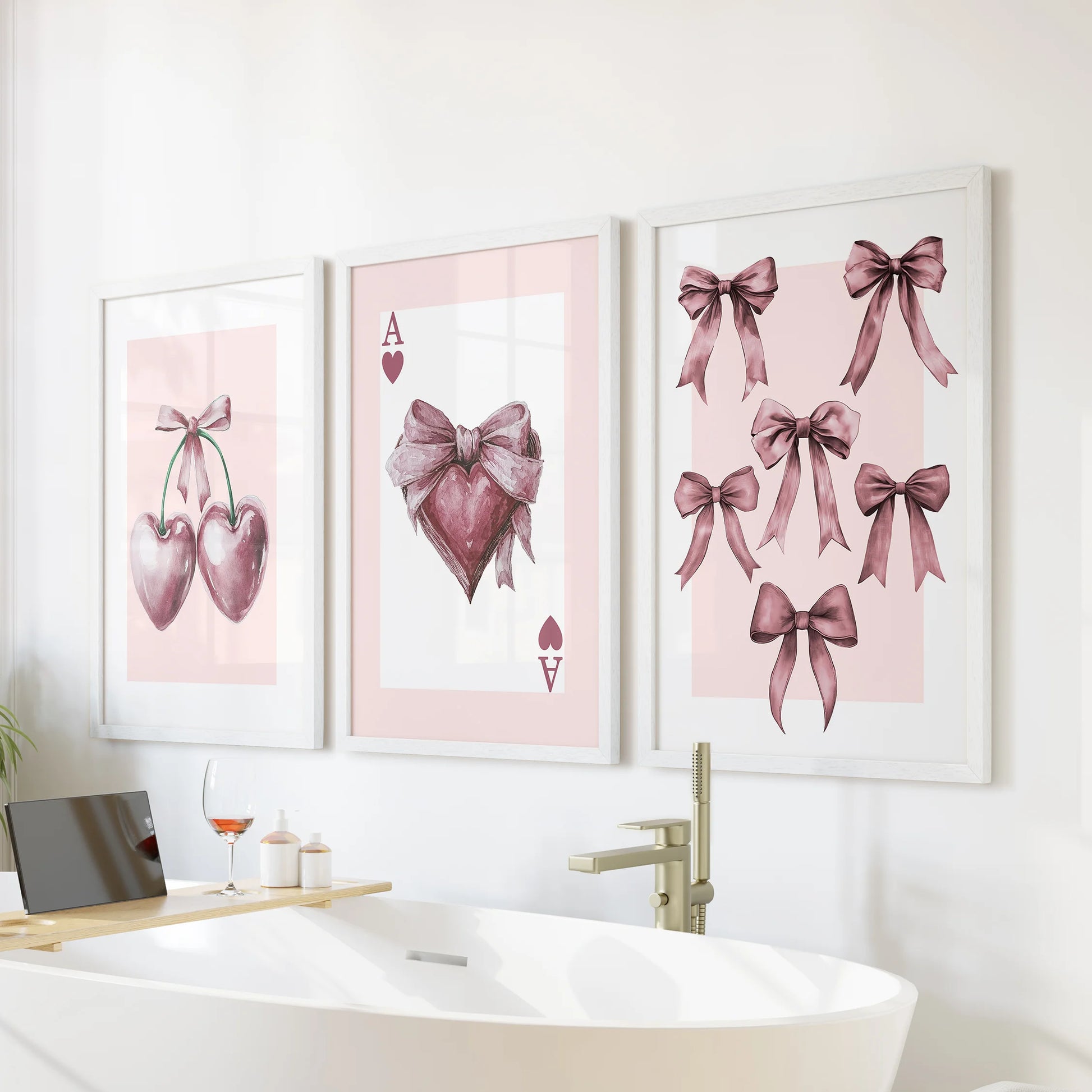White-framed art prints of the Ace of Hearts form a three-piece set above a freestanding tub, giving the bathroom wall a chic blush detail.