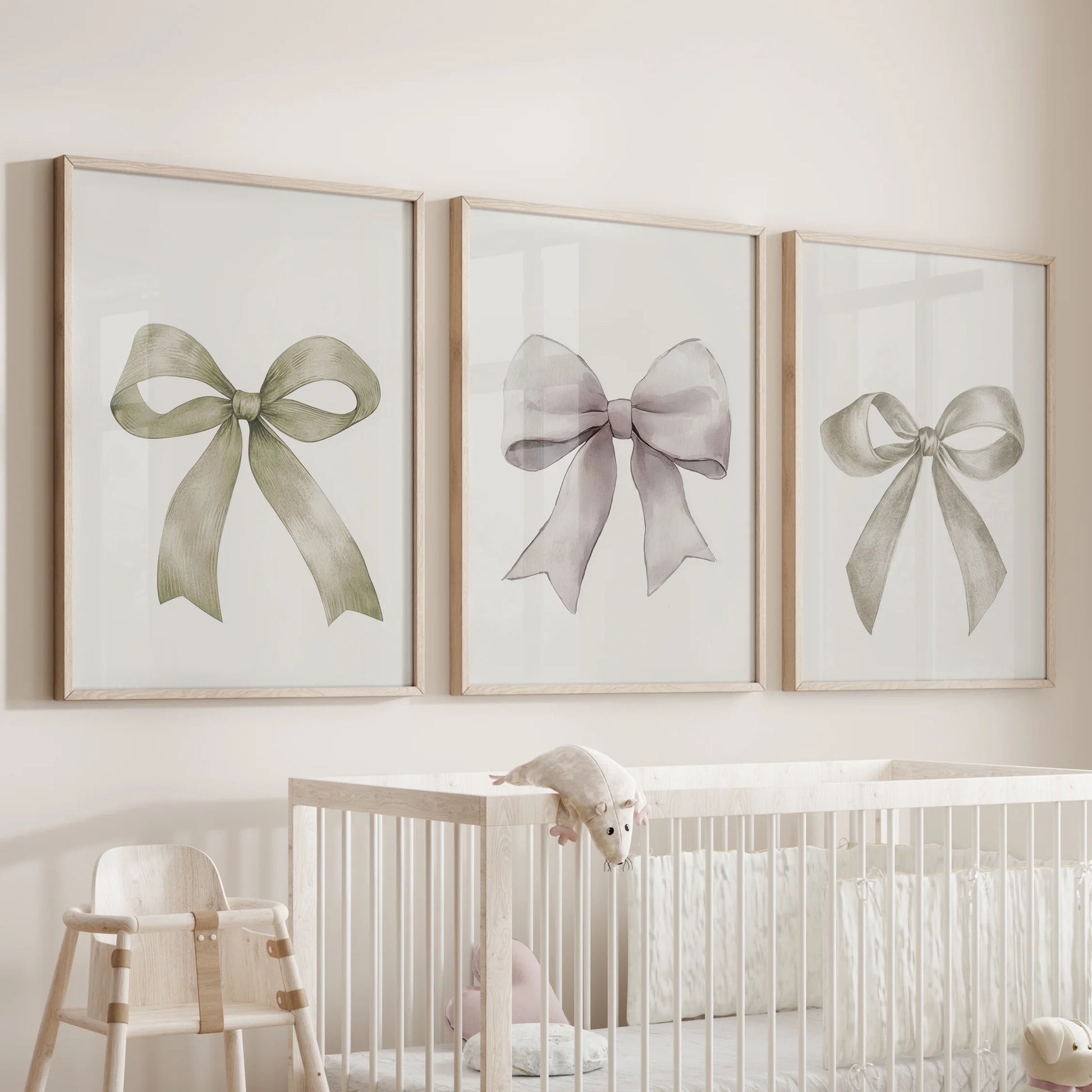 Three coquette bow artworks in light oak frames hover above the nursery bassinet, bringing soft ribbon curves to a calm, neutral nook.