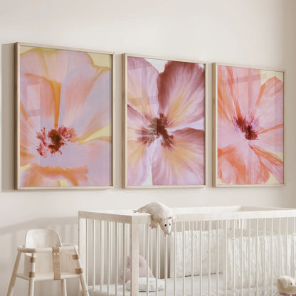 Three pastel flower close-up prints hang above a nursery crib, framed in oak.