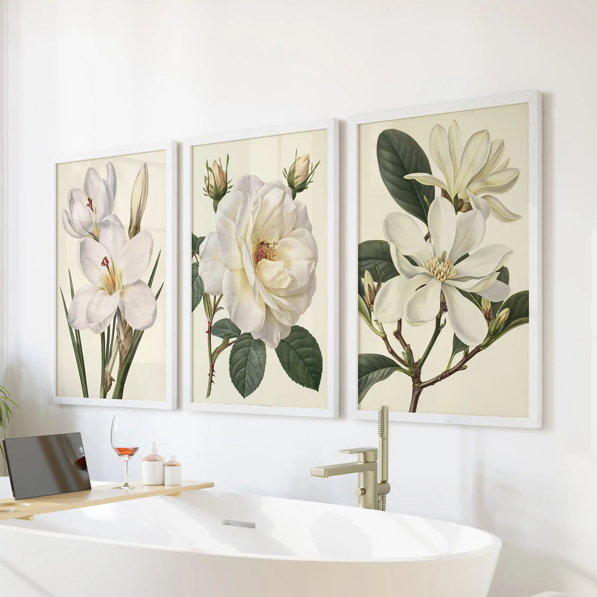 White flower studies hang in three white frames above a freestanding bathtub.