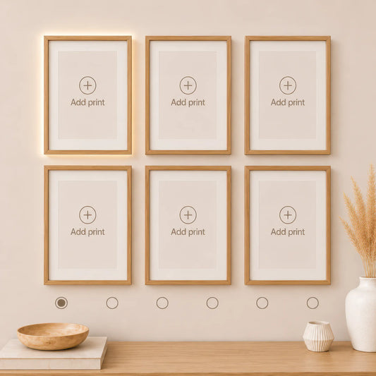 Interactive wall art builder with six empty natural wood frames displayed in two rows of three. Preview and create a personalized gallery wall with matching art prints.