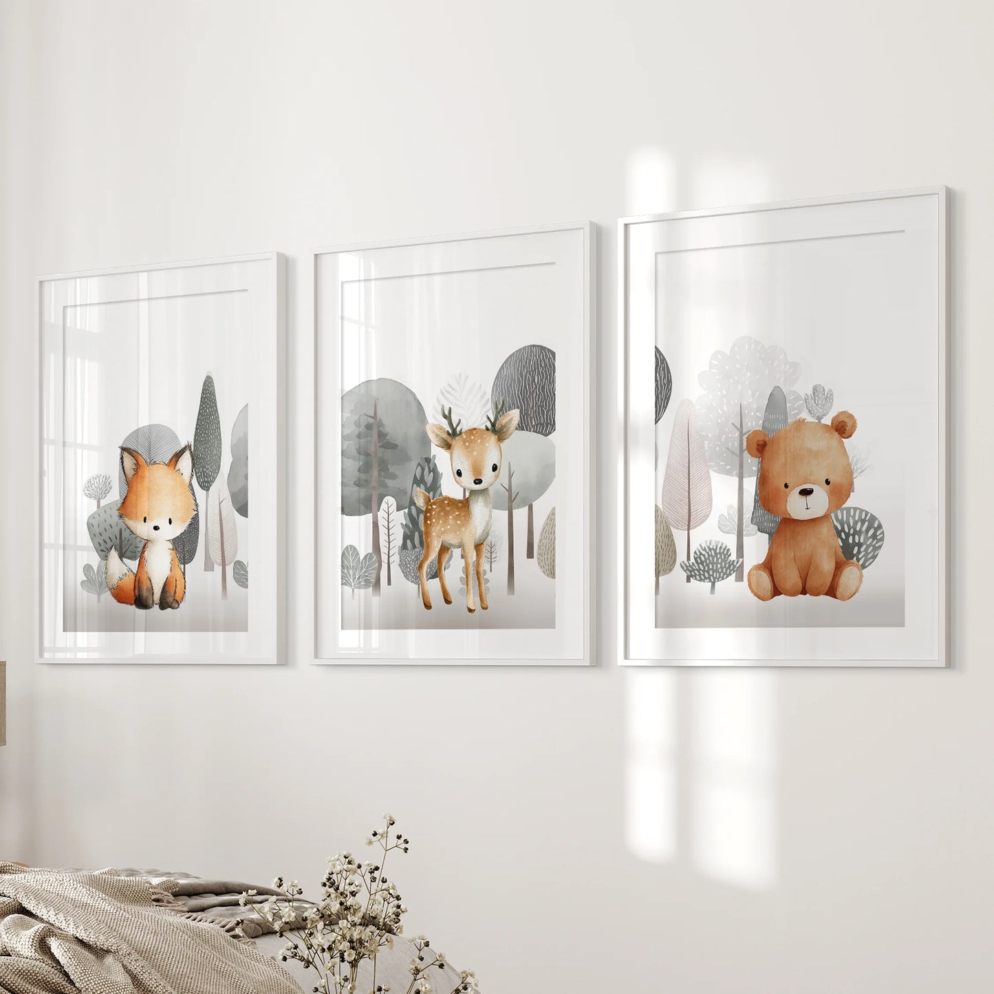 A matted trio of fox, fawn, and teddy bear prints, framed in white, rests neatly on the bedroom's bedside wall.