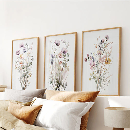 Thin wood-framed spring florals compose a three-piece wall decor set stretching over the bed headboard, lending sunlit color to the bedroom.