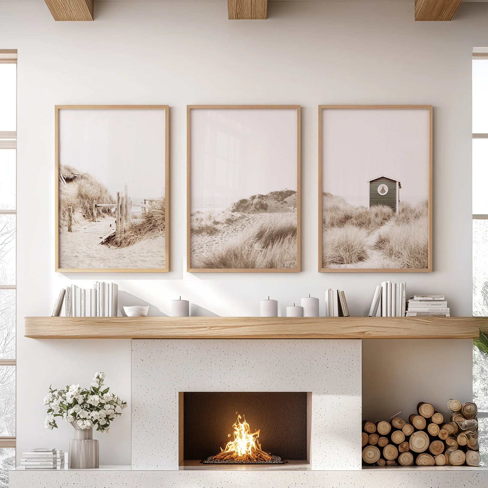 Three wood-framed wall prints of dried coastal grass rest above the fireplace, introducing organic texture and relaxed neutral calm.