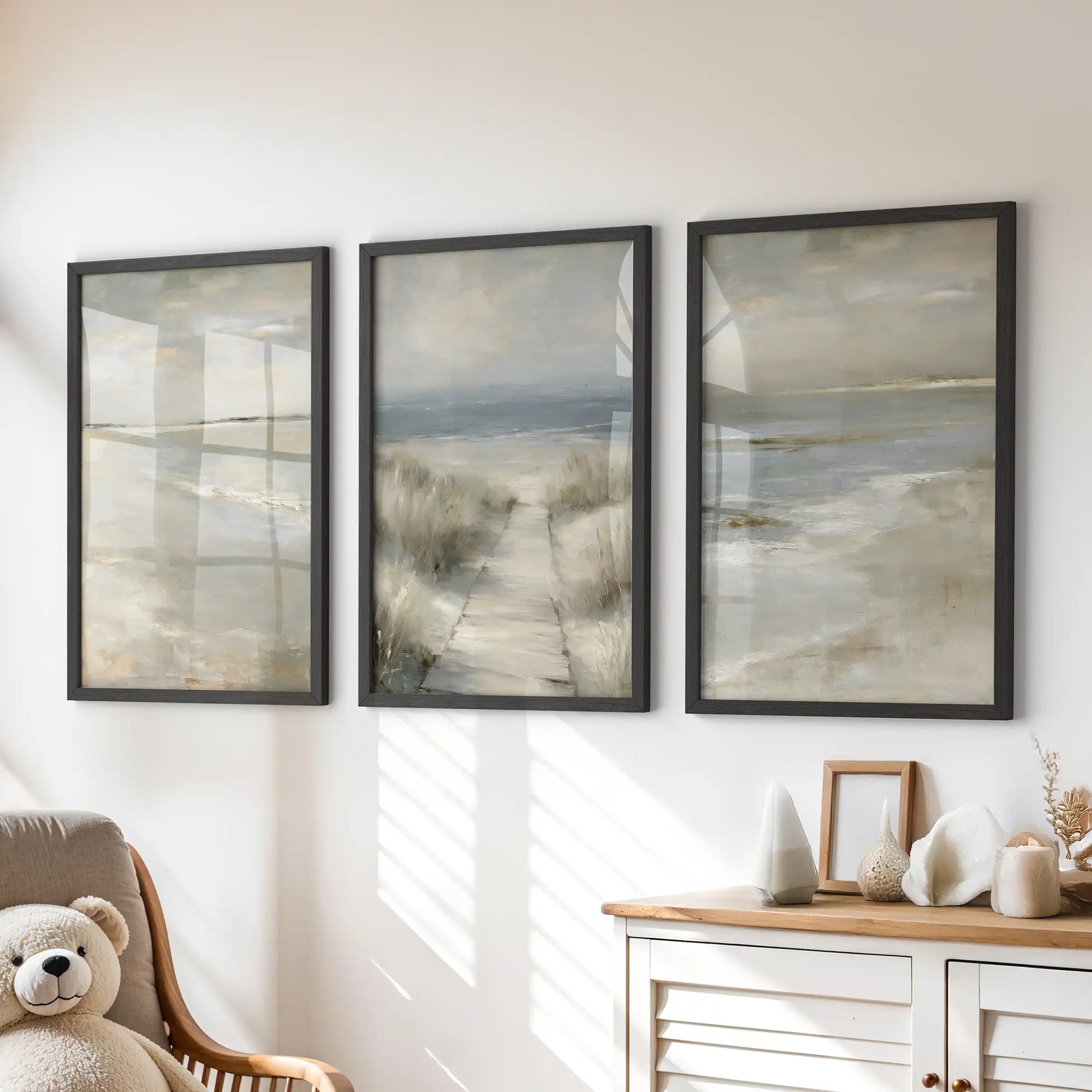 Black-framed wall art of soft sand textures, a set of three prints, floats above the chest of drawers for a gentle coastal mood in the children’s room.