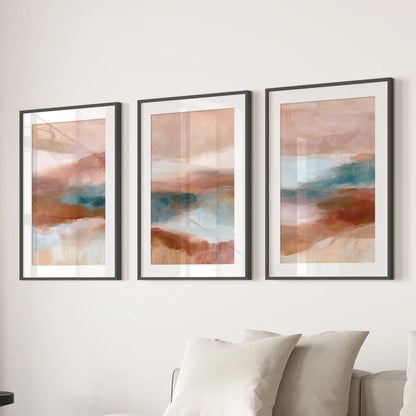 Three art prints form an earth-tone abstract triptych, finished with black mats and frames above the sectional sofa in the sitting room.
