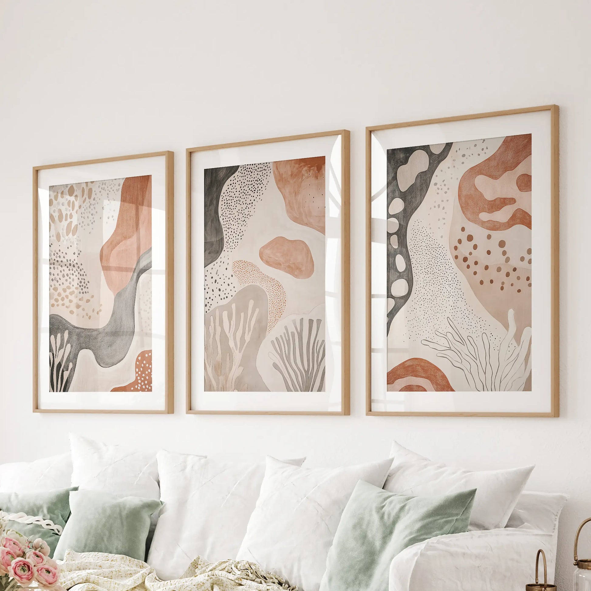 Set of three earthy geometric prints in natural wood matted frames lifts the lounge wall above the sofa with relaxed texture.