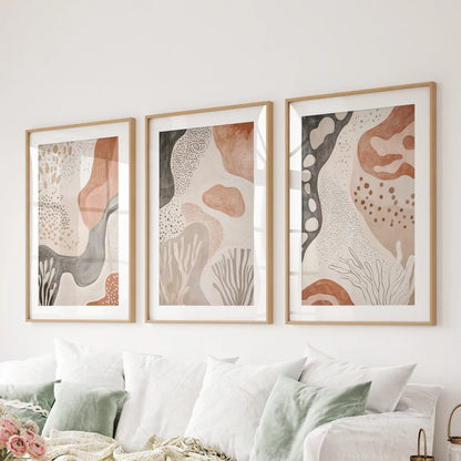 Set of three earthy geometric prints in natural wood matted frames lifts the lounge wall above the sofa with relaxed texture.