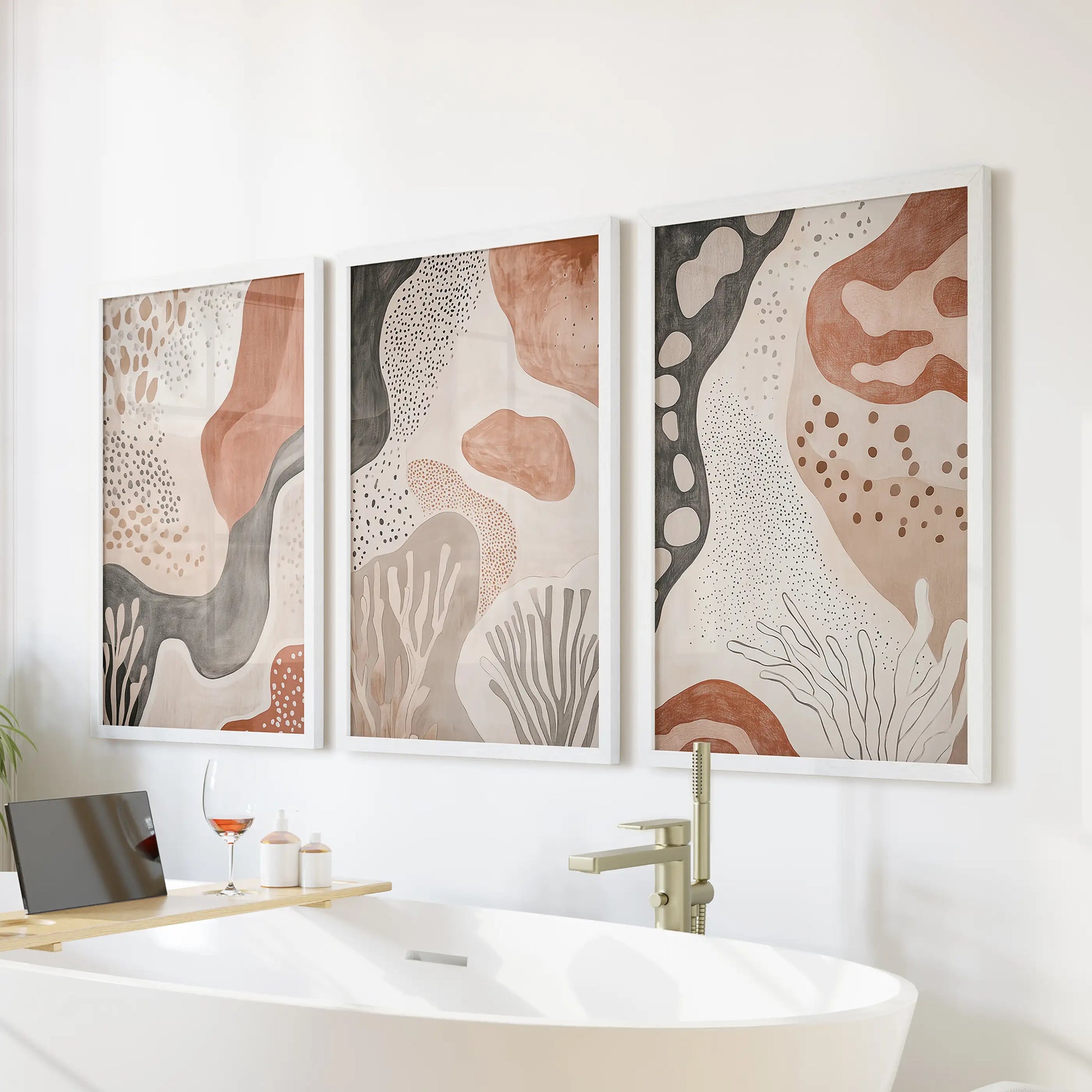 Earthy mid-century geometrics, a trio of wall prints in crisp white frames, bring soft warmth above the tub for a serene bathroom vignette.