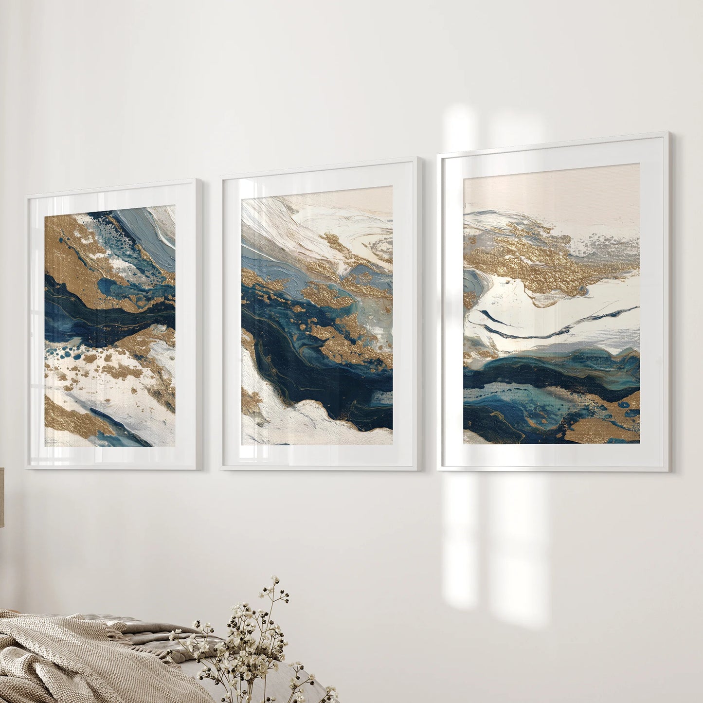 Three framed abstract prints with white mats line the bedroom wall beside the bed, their blue and beige tones giving a serene, modern accent.