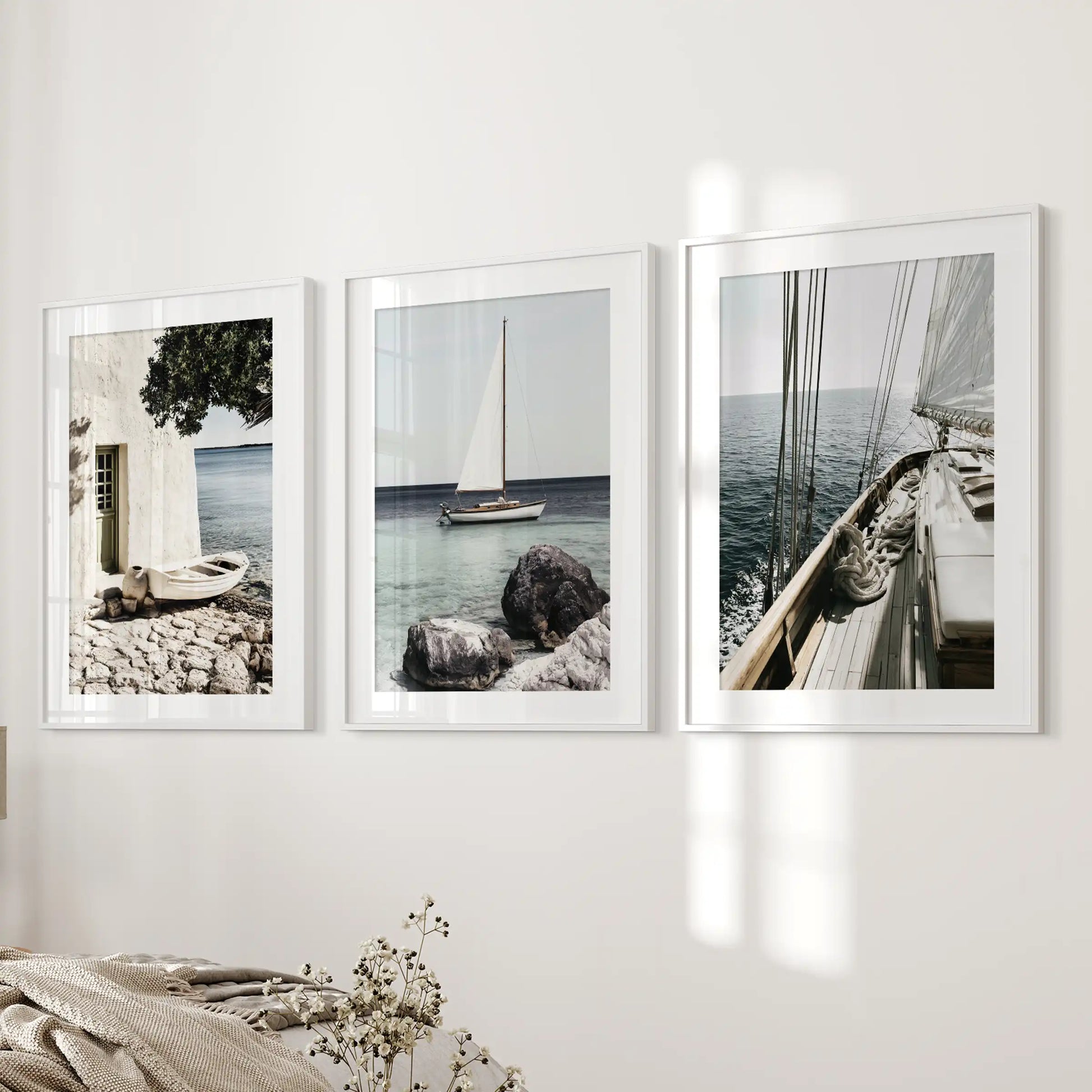 A 3-wall-art set of sailboats features white frames with wide mats and hangs next to the bed, giving the bedroom a serene, tide-washed feel.